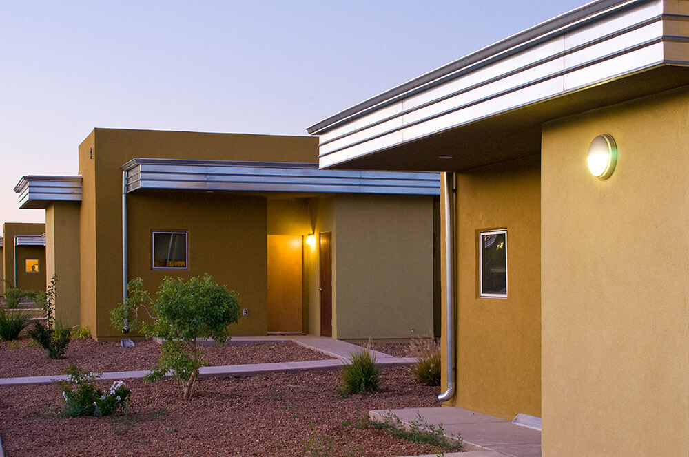 Private front doors glowing with warm entry lights at dusk at Wilshire Gardens senior apartments in Roswell