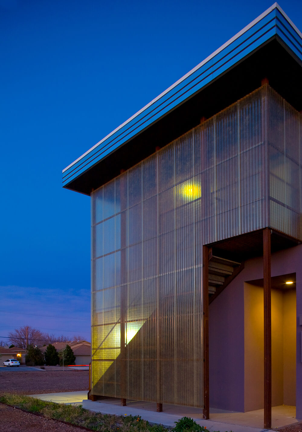 Community building at Wilshire Gardens with translucent wall panels glowing from within at dusk in Roswell, New Mexico